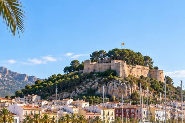 Dénia castle on its wooded hill above pastel-coloured houses and the masts of the marina